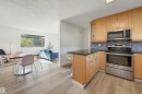 Stainless steel appliances, wood-finish flooring, light wood cabinetry, dark countertop, and mosaic tile backsplash - 9127 149 Street Nw, Edmonton, AB  - Indoor Photo Showing Kitchen 