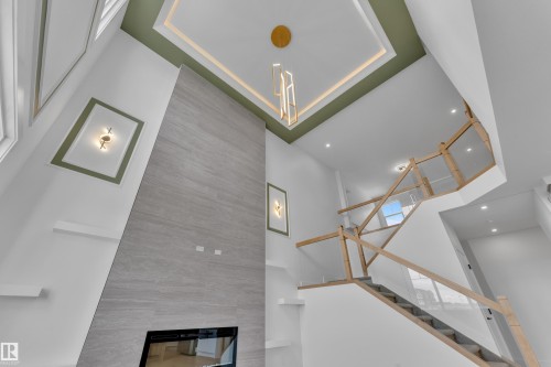 Two-story living area with a built-in linear fireplace, a floor-to-ceiling accent wall, and a custom staircase with glass panels - 764 Astoria Way, Devon, AB - Indoor Photo Showing Other Room