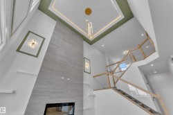 Two-story living area with a built-in linear fireplace, a floor-to-ceiling accent wall, and a custom staircase with glass panels - 