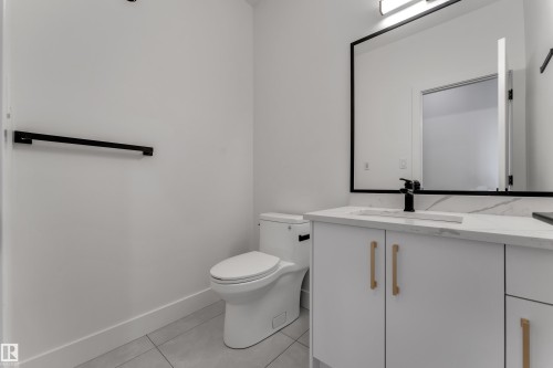 White vanity with gold-finish hardware, rectangular undermount sink, and a black-framed mirror - 764 Astoria Way, Devon, AB - Indoor Photo Showing Bathroom