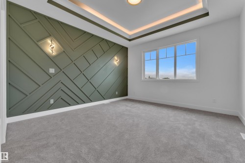 Accent wall with geometric trim, two wall-mounted sconces, large multi-pane window, recessed ceiling lighting, and grey carpet flooring - 764 Astoria Way, Devon, AB - Indoor Photo Showing Other Room
