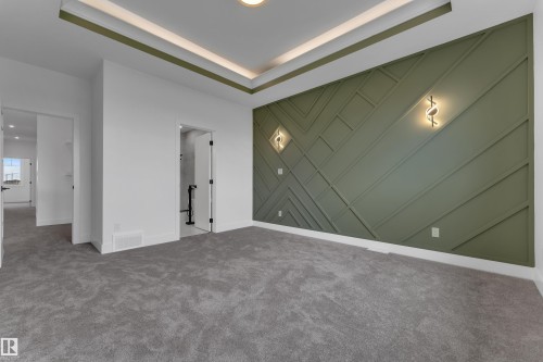 Recessed ceiling lighting, tray ceiling detail, feature wall with geometric paneling, decorative wall sconces, and neutral-toned carpeting - 764 Astoria Way, Devon, AB - Indoor Photo Showing Other Room