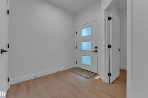Entryway featuring wood-finish flooring and a modern door with frosted glass inserts - 764 Astoria Way, Devon, AB - Indoor Photo Showing Other Room