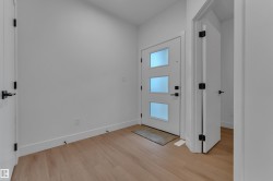 Entryway featuring wood-finish flooring and a modern door with frosted glass inserts - 