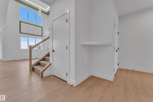 Tall ceilings with a contemporary chandelier, large windows with natural light, wood-finish flooring, a staircase with carpeting, and white interior doors - 764 Astoria Way, Devon, AB - Indoor Photo Showing Other Room