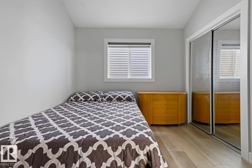 Light gray walls, wood-finish flooring, white window trim, and mirrored closet doors - 11816 168 Avenue Nw, Edmonton, AB - Indoor Photo Showing Bedroom
