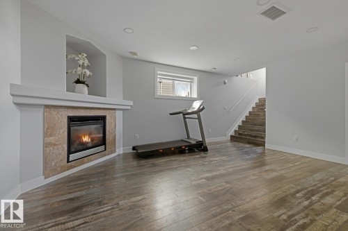 Wood-finish flooring, recessed lighting, and a corner fireplace with a tiled surround - 11816 168 Avenue Nw, Edmonton, AB - Indoor With Fireplace