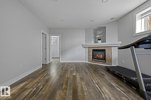 Wood-finish flooring, recessed lighting, and a corner fireplace with a stone surround - 11816 168 Avenue Nw, Edmonton, AB - Indoor With Fireplace