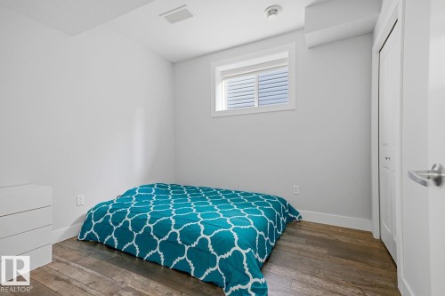 Room featuring wood-finish flooring, a window with blinds, and a white bi-fold closet door - 11816 168 Avenue Nw, Edmonton, AB - Indoor Photo Showing Bedroom