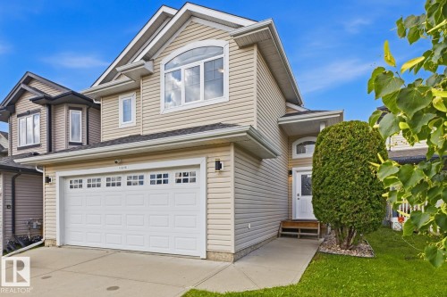 Two-story residence featuring light-colored siding and a two-car garage with paneling and upper windows - 11816 168 Avenue Nw, Edmonton, AB - Outdoor