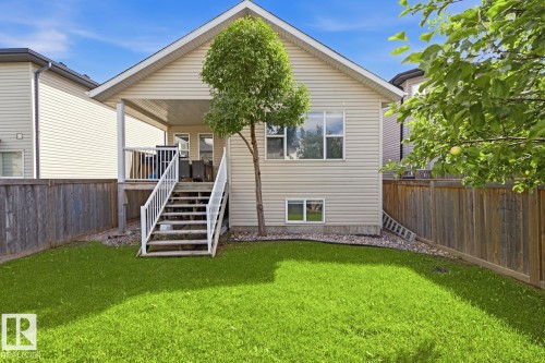 Expansive fenced backyard featuring a manicured lawn, a covered deck, and a full-height exterior access staircase - 11816 168 Avenue Nw, Edmonton, AB - Outdoor