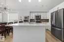 Kitchen featuring a white island with an integrated sink, stainless steel appliances, white cabinetry, and wood-finish flooring - 11816 168 Avenue Nw, Edmonton, AB  - Indoor Photo Showing Kitchen With Double Sink With Upgraded Kitchen 