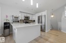 Kitchen featuring light wood-finish flooring, white cabinetry, stainless steel appliances, and a central island with a light-toned countertop - 11816 168 Avenue Nw, Edmonton, AB  - Indoor Photo Showing Kitchen With Upgraded Kitchen 