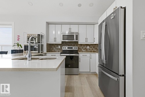Kitchen featuring light wood-finish flooring, white cabinetry, stainless steel appliances, a tiled backsplash, and recessed lighting - 11816 168 Avenue Nw, Edmonton, AB - Indoor Photo Showing Kitchen