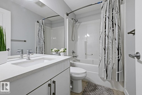 Bathroom featuring a single vanity with an integrated sink, polished chrome faucet, and a large wall-mounted mirror - 11816 168 Avenue Nw, Edmonton, AB - Indoor Photo Showing Bathroom