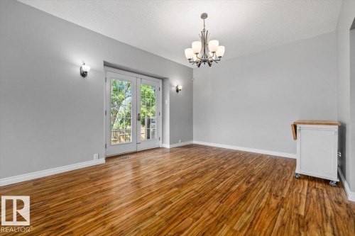 Wood-finish flooring, French doors, wall sconces, ceiling-mounted chandelier - 11429 64 Street Nw, Edmonton, AB - Indoor Photo Showing Other Room