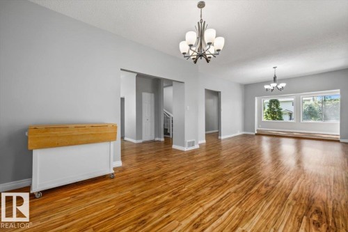 Expansive wood-finish flooring throughout, two decorative chandeliers, and multiple large windows providing ample natural light - 11429 64 Street Nw, Edmonton, AB - Indoor
