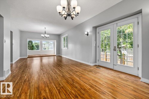 Spacious interior featuring wood-finish flooring, light gray walls, and multiple light fixtures - 11429 64 Street Nw, Edmonton, AB - Indoor Photo Showing Other Room