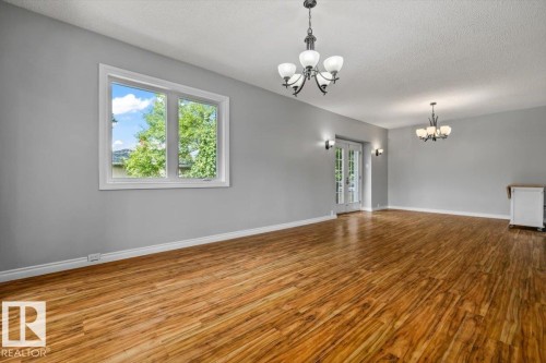 Wood-finish flooring, white trim, multiple chandeliers, wall sconces, and French doors - 11429 64 Street Nw, Edmonton, AB - Indoor Photo Showing Other Room
