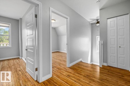 Wood-finish flooring throughout, light gray wall paint, white trim, and white paneled doors - 11429 64 Street Nw, Edmonton, AB - Indoor Photo Showing Other Room