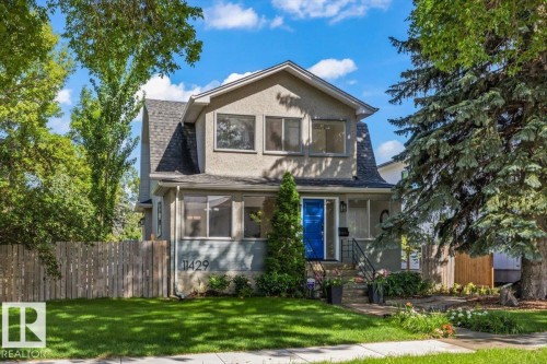 Stucco exterior, prominent front entry with a bright blue door, mature landscaping, paved walkway, and a partial privacy fence - 11429 64 Street Nw, Edmonton, AB - Outdoor