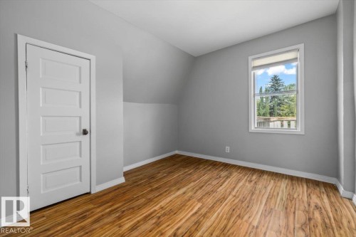 Wood-finish flooring, white trim, single window, paneled door, and sloped ceiling - 11429 64 Street Nw, Edmonton, AB - Indoor Photo Showing Other Room