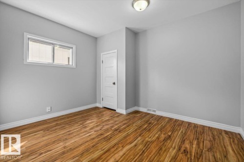 Recessed window, wood-finish flooring, white trim, five-panel interior door, and flush-mount ceiling light fixture - 11429 64 Street Nw, Edmonton, AB - Indoor Photo Showing Other Room