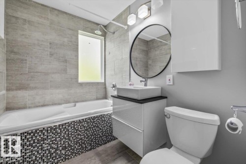 Tiled bath surround with mosaic accents, floating vanity with vessel sink, and rectangular shower window - 11429 64 Street Nw, Edmonton, AB - Indoor Photo Showing Bathroom