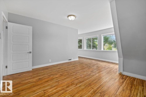 Wood-finish flooring, multiple windows, contemporary door with horizontal panels, neutral wall color, and a flush mount ceiling light - 11429 64 Street Nw, Edmonton, AB - Indoor Photo Showing Other Room