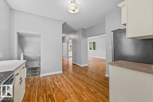 Wood-finish flooring throughout, with white cabinetry and light-toned countertops - 11429 64 Street Nw, Edmonton, AB - Indoor Photo Showing Kitchen