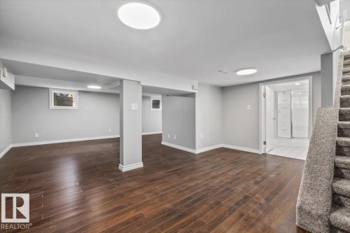 Spacious lower level featuring wood-finish flooring, recessed lighting, neutral wall tones, and a bathroom with a glass-enclosed shower - 11429 64 Street Nw, Edmonton, AB - Indoor