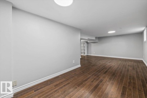Spacious room featuring wood-finish flooring, light gray walls, built-in recessed lighting, and a white built-in shelving unit - 11429 64 Street Nw, Edmonton, AB - Indoor Photo Showing Other Room