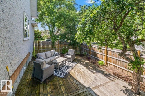 Expansive wooden deck with a privacy fence, mature trees, and stucco exterior - 11429 64 Street Nw, Edmonton, AB - Outdoor With Deck Patio Veranda