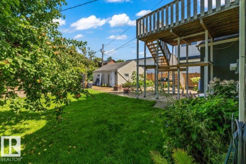 Spacious backyard featuring a manicured lawn, established landscaping, mature shade tree, and a two-story wood-frame deck - 11429 64 Street Nw, Edmonton, AB - Outdoor