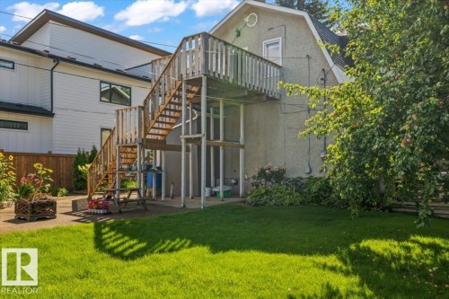 Expansive backyard featuring a lush lawn, mature trees, and an elevated wood deck with stair access - 11429 64 Street Nw, Edmonton, AB - Outdoor
