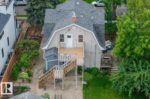 Rear exterior featuring a gambrel roofline, elevated wood deck with stairs, additional ground-level wood deck, and a detached structure with a pitched roof - 11429 64 Street Nw, Edmonton, AB - Outdoor