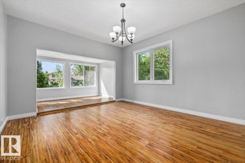 Wood-finish flooring, recessed area with triple windows, white window trim, contemporary chandelier, and light gray wall color - 11429 64 Street Nw, Edmonton, AB - Indoor Photo Showing Other Room
