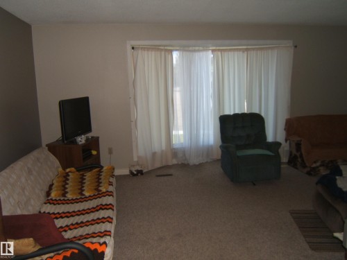 Carpeted flooring, neutral wall colors, and a large window providing natural light - 5404 49 Street, Two Hills, AB - Indoor