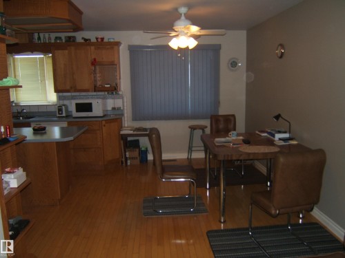 Kitchen featuring wood-finish flooring, wood cabinetry, a built-in microwave, and a breakfast bar - 5404 49 Street, Two Hills, AB - Indoor