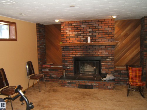 Brick fireplace with a wood mantel - 5404 49 Street, Two Hills, AB - Indoor With Fireplace