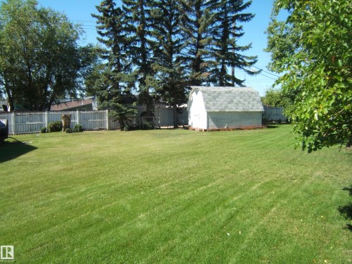 Expansive lawn with a detached storage shed, perimeter fencing, and mature trees - 5404 49 Street, Two Hills, AB - Outdoor