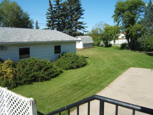Expansive backyard featuring a manicured lawn, mature trees, and a detached shed - 5404 49 Street, Two Hills, AB - Outdoor