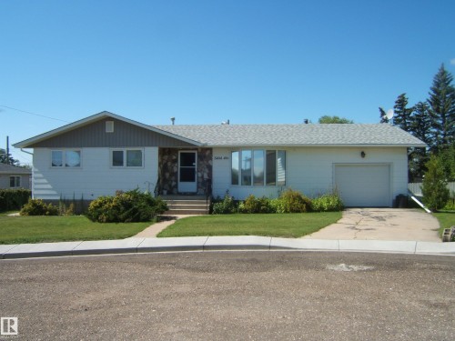 Ranch-style exterior with stone facade accents, an attached garage, and a concrete driveway - 5404 49 Street, Two Hills, AB - Outdoor With Facade