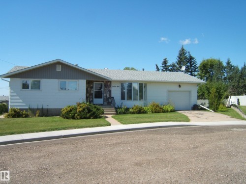 Single-story residence featuring a front entry with stone facade accents, an attached garage, and a concrete driveway - 5404 49 Street, Two Hills, AB - Outdoor With Facade