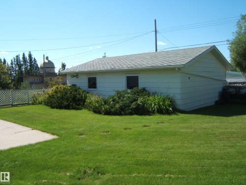 Single-story residence featuring horizontal siding, a gabled roof, and foundational landscaping - 5404 49 Street, Two Hills, AB - Outdoor