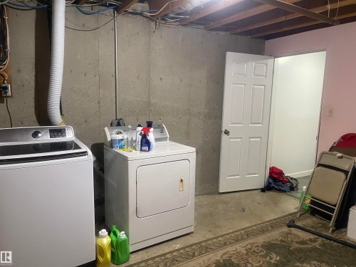 Basement utility area featuring concrete walls, exposed ceiling joists, and a paneled door - 3221 132A Avenue Nw, Edmonton, AB - Indoor Photo Showing Laundry Room