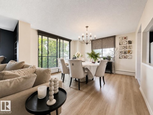 Bright dining area featuring wood-finish flooring and a multi-light chandelier - #301 9808 103 St Nw, Edmonton, AB - Indoor