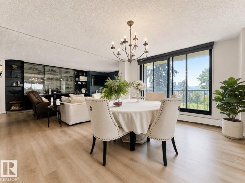 Dining area with chandelier illumination, featuring light wood-finish flooring, and expansive sliding glass doors - #301 9808 103 St Nw, Edmonton, AB - Indoor Photo Showing Dining Room