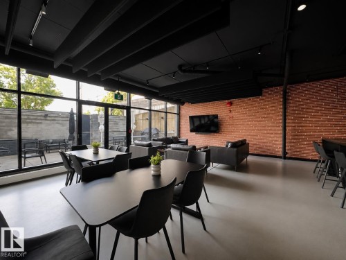 Spacious communal area featuring extensive window walls, exposed brick accent wall, and recessed ceiling lighting - #301 9808 103 St Nw, Edmonton, AB -  Photo Showing Dining Room