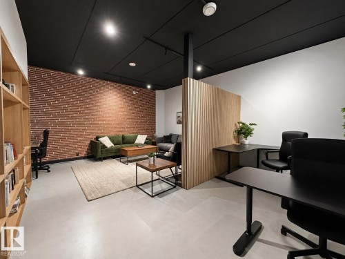 Open-concept space featuring a textured brick accent wall and light wood flooring - #301 9808 103 St Nw, Edmonton, AB - Indoor Photo Showing Office